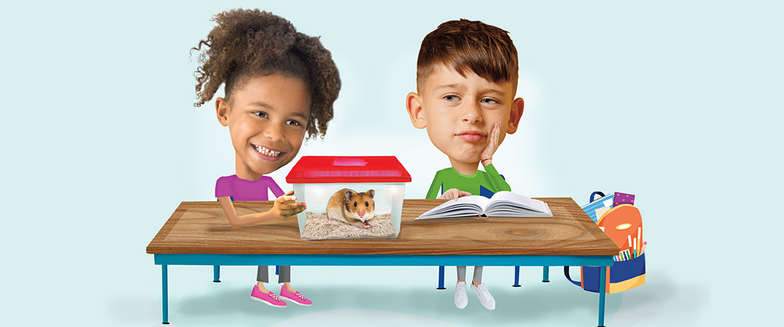 Image of students sitting at desk with pet hamster on top